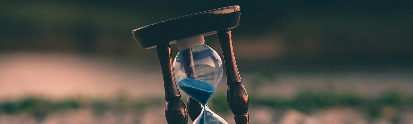 A tilted hourglass resting on pebbles