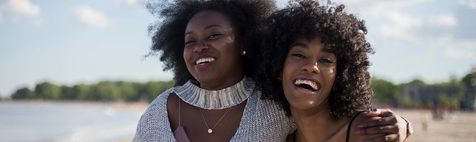 two young black girls walking on a beach embracing and happy and enjoying life