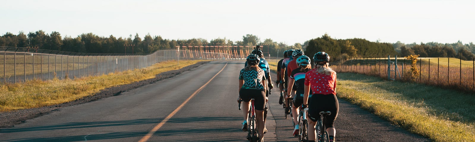 A group of cyclists, riding down a deserted paved road.