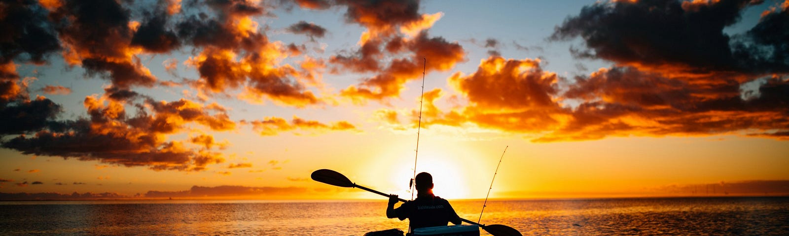 fisherman paddling in a boat toward the sunset