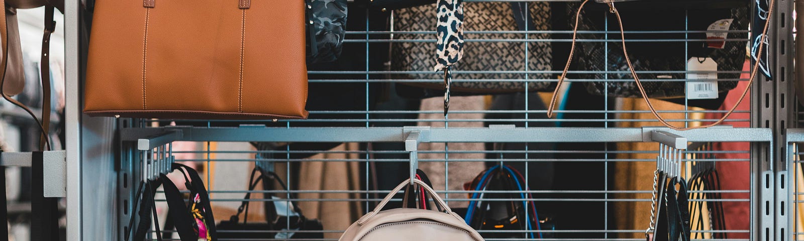 Many purses hang on a sales rack