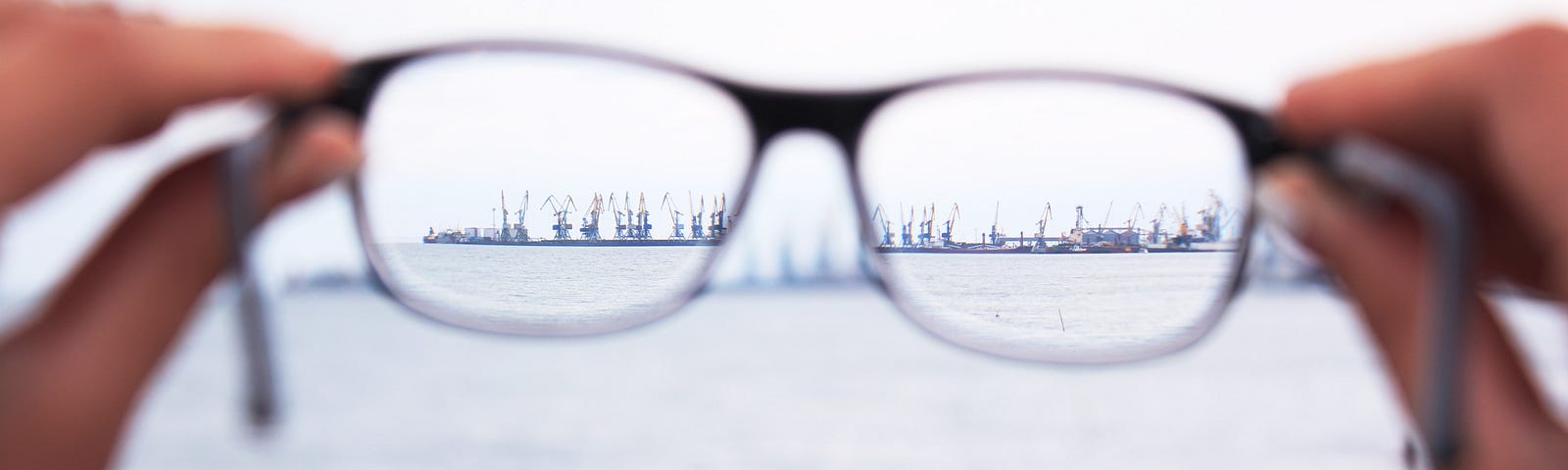 Holding glasses up to see a skyline. The focus is clear in the lenses of the glasses.