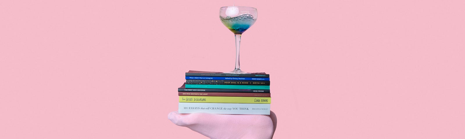 Person balancing books on their feet with a glass of water on top of the books, there is a pink background