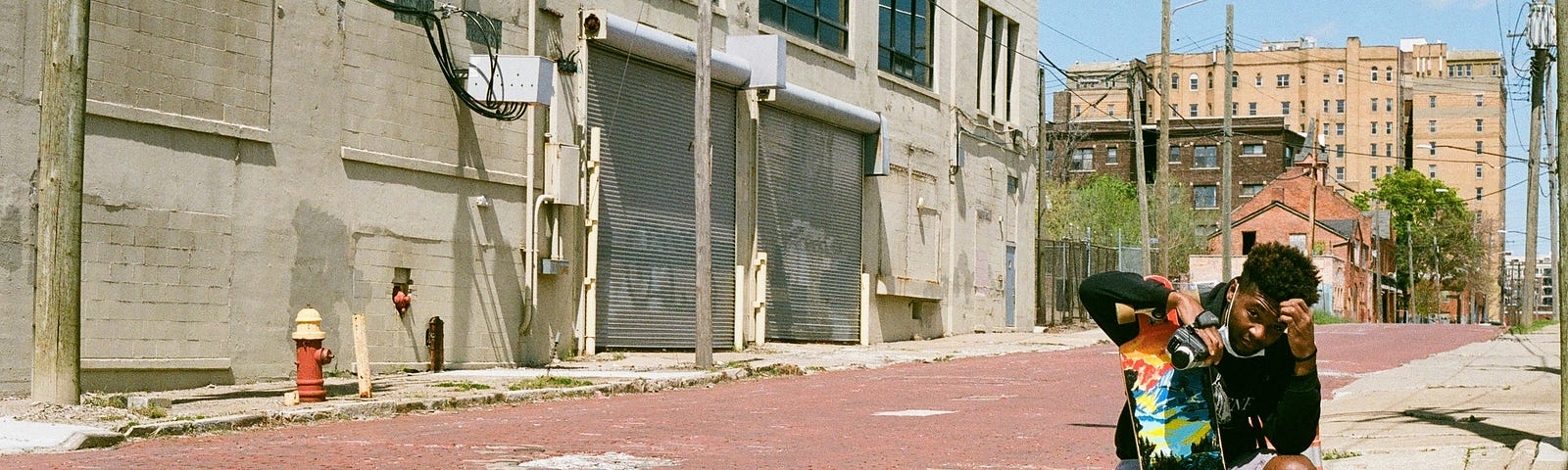 a man outside near an empty looking building with a skateboard