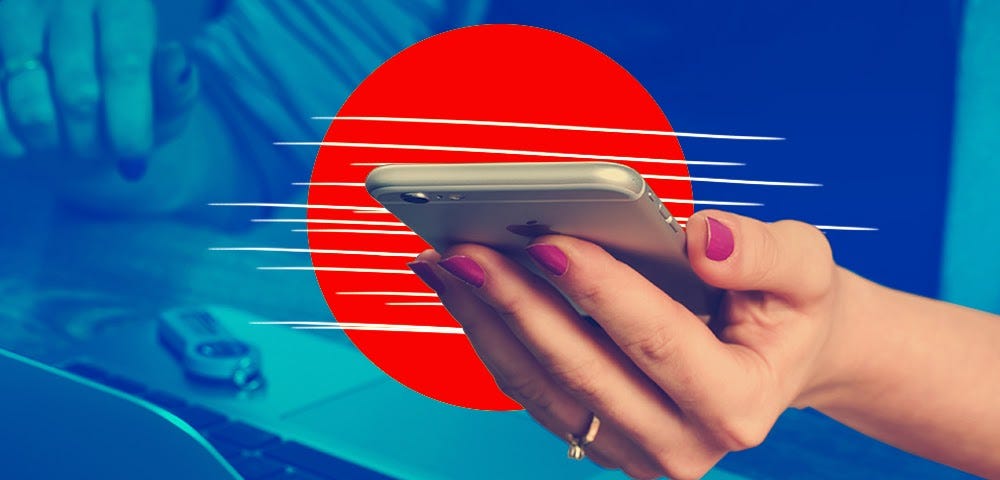 woman’s hand holding silver iphone in front of red circle, above an opened laptop in blue background