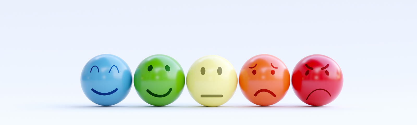 photograph of five different colored small balls lined up in a row with different expressions of happiness to pain on their faces