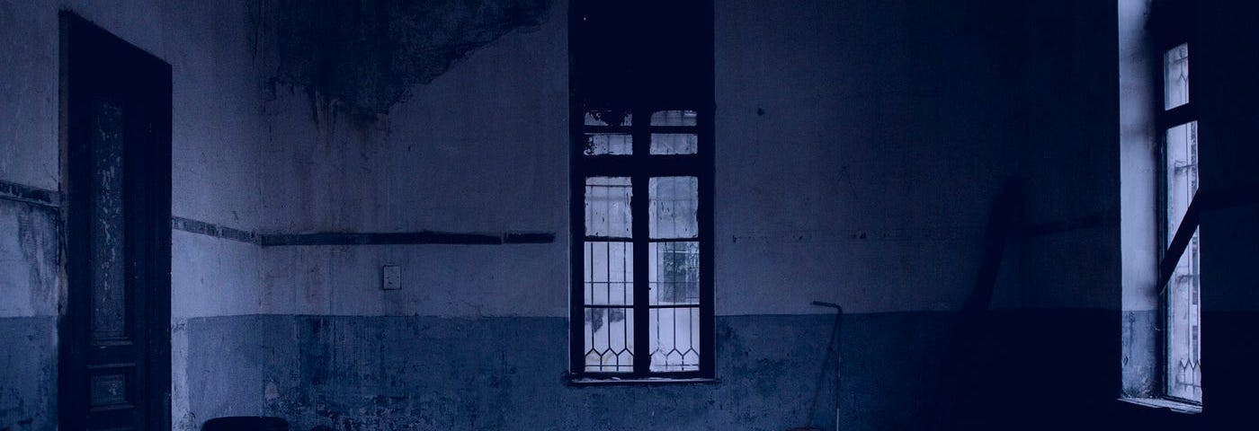 a dark, damp, abandoned room. There is one armchair.