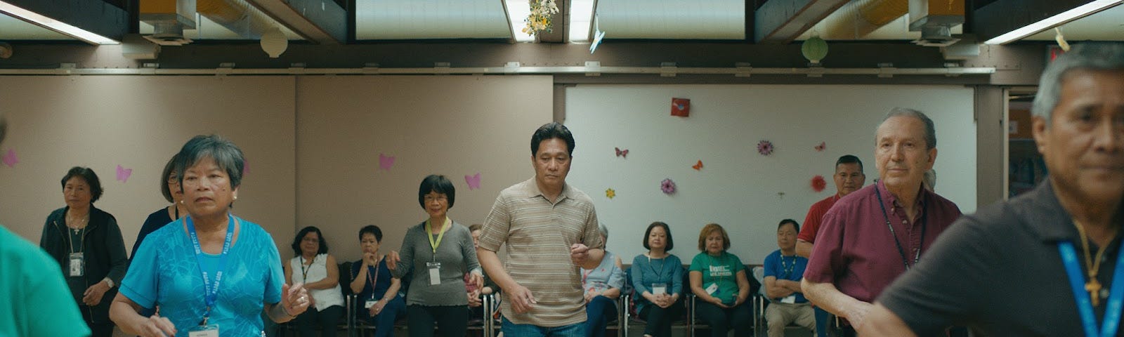 Film still from ISLANDS of Joshua dancing in a senior line dance class, with other seniors dancing along