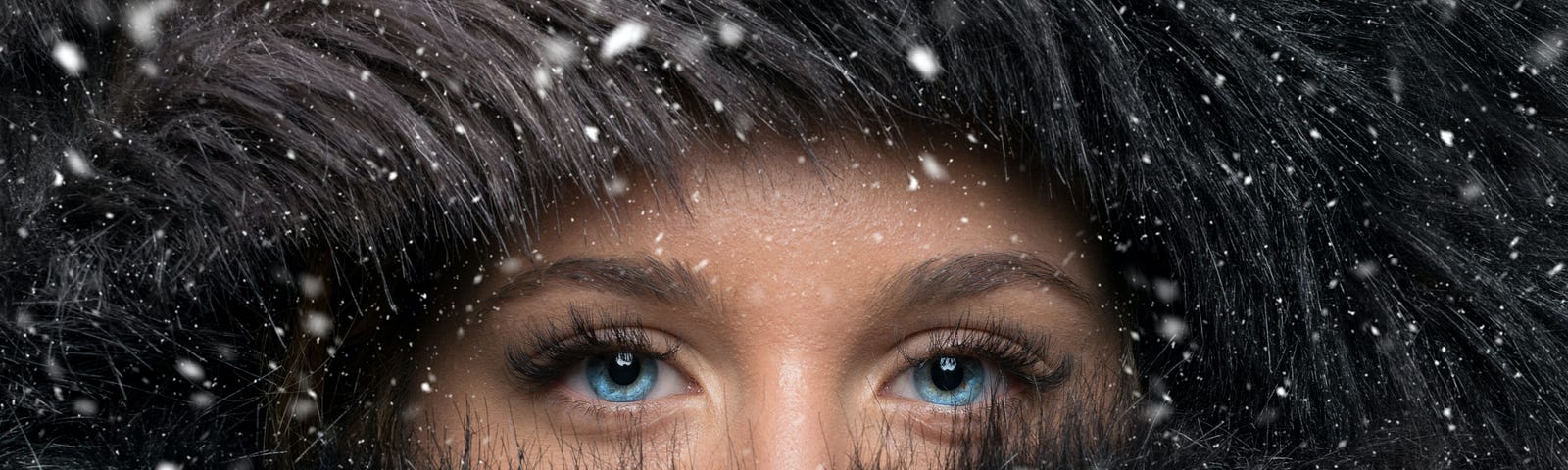 a blue-eyed woman wrapped in fur, out in the snow