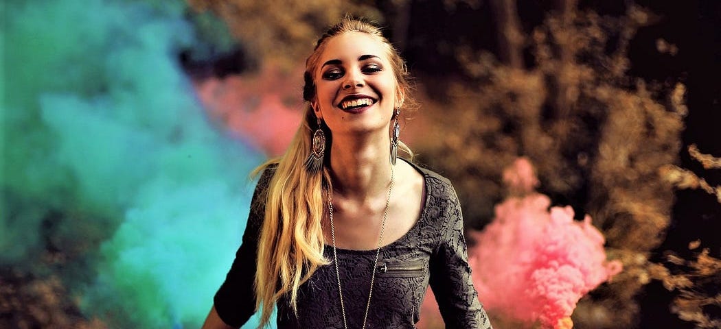 smiling girl with long brown hair holding green and pink flares