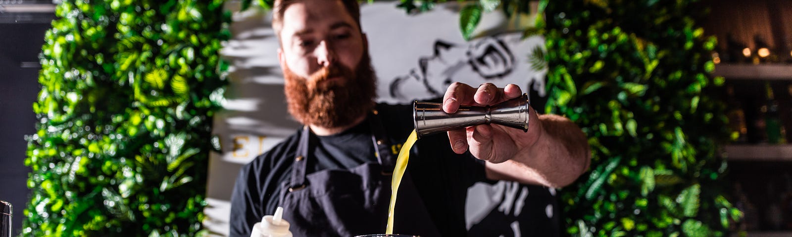 Image of a bartender pouring a drink from a cocktail shaker