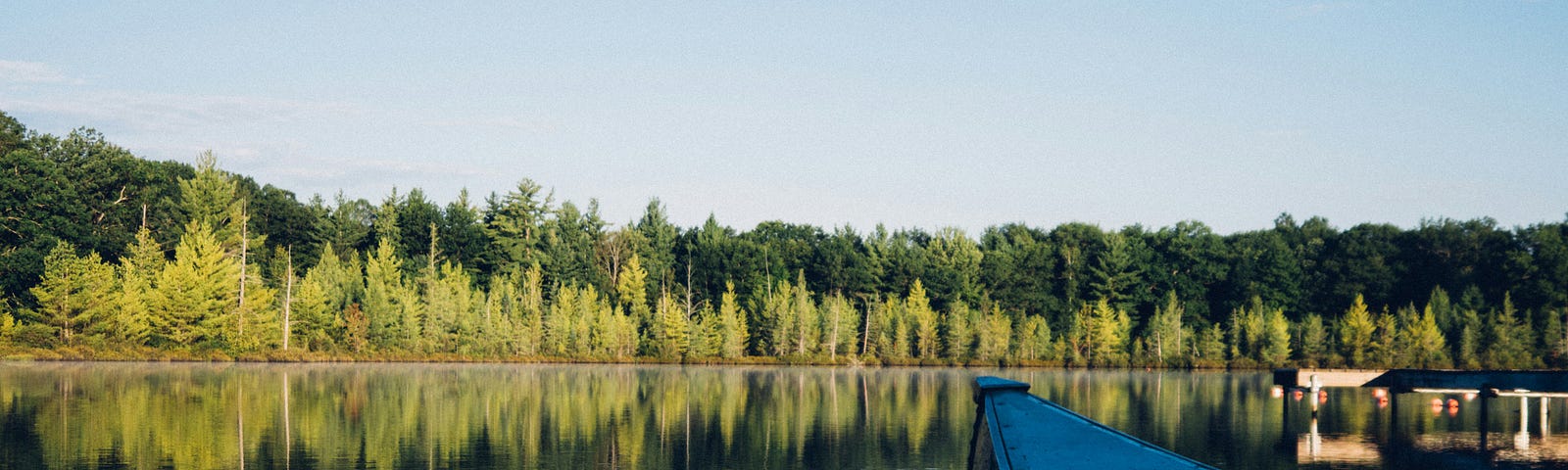 boat at the dock on a still lake.