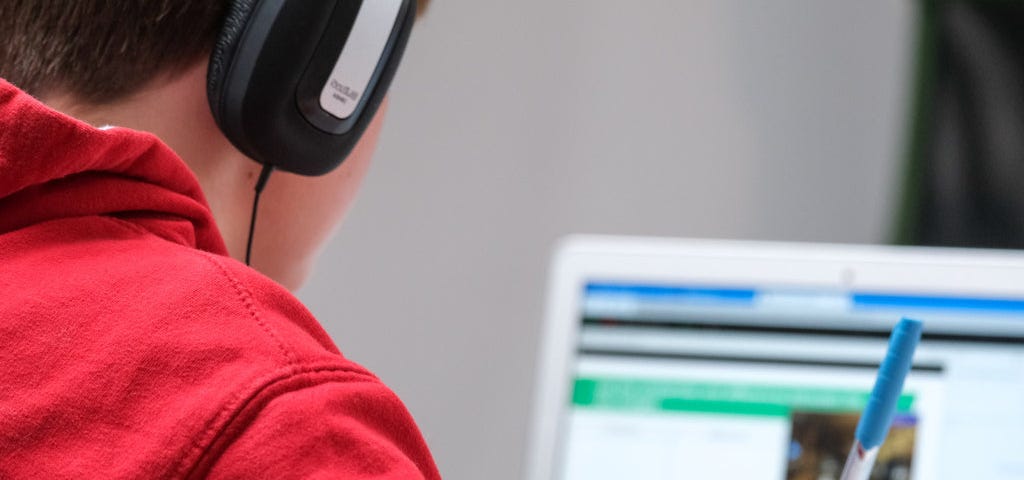 man working on a laptop wearing headphones