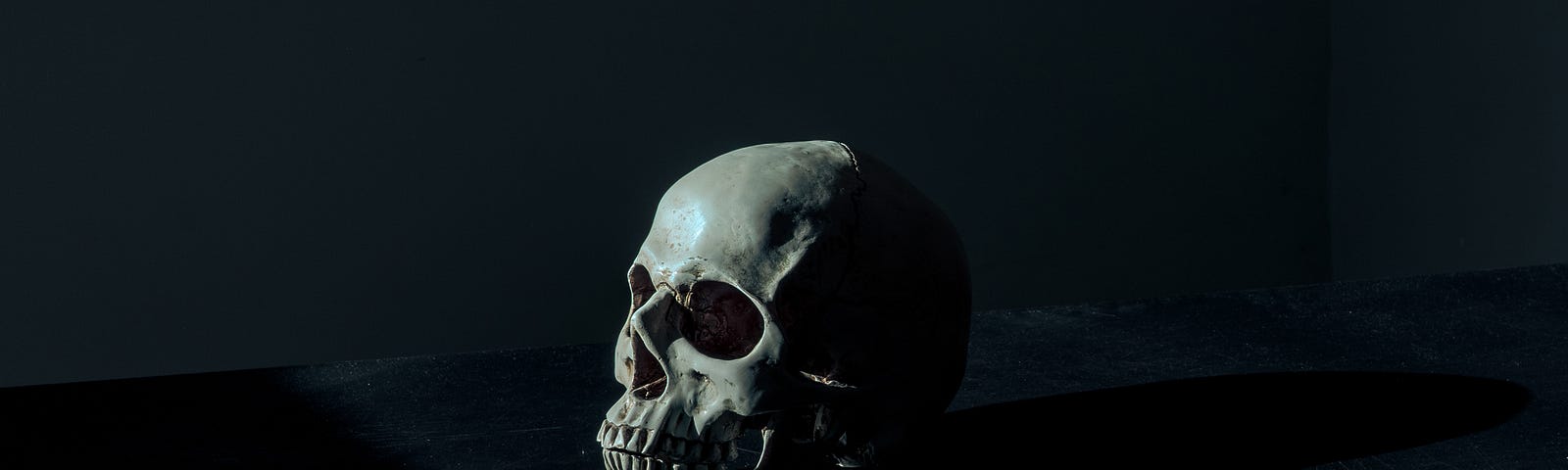 A human skull resting on a table, with a dark background.