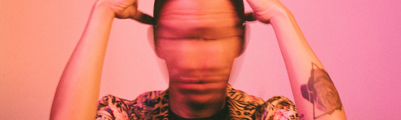 Man shaking head really quickly so his face is blurred with his hands at his head. Frustrated with the million thoughts running through his head.