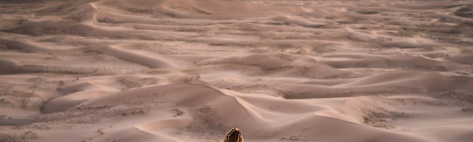 Person sitting in the desert, watching the sands of time.