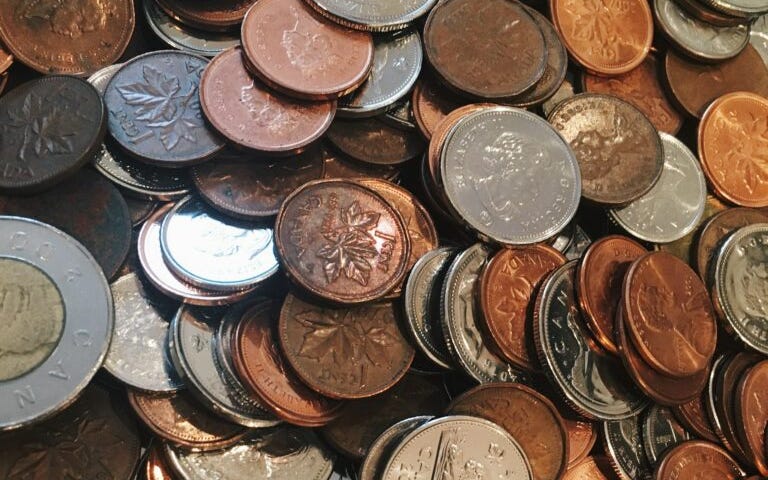 A pile of loose Canadian change and a 5 cent coin with a beaver in the middle. Image courtesy of Pina Messina at Unsplash.