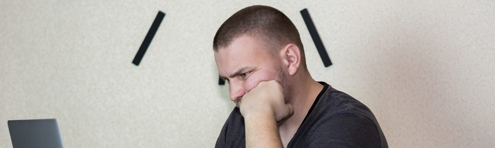 Man looking at his laptop with a frustrated expression.