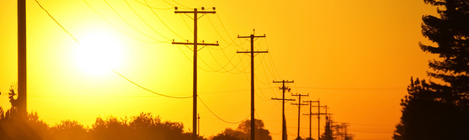 Road at sunset with power lines running next to it.