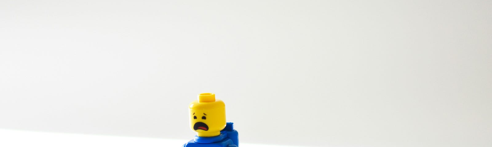 Lego man with blue clothes and a yellow head with panicky face.