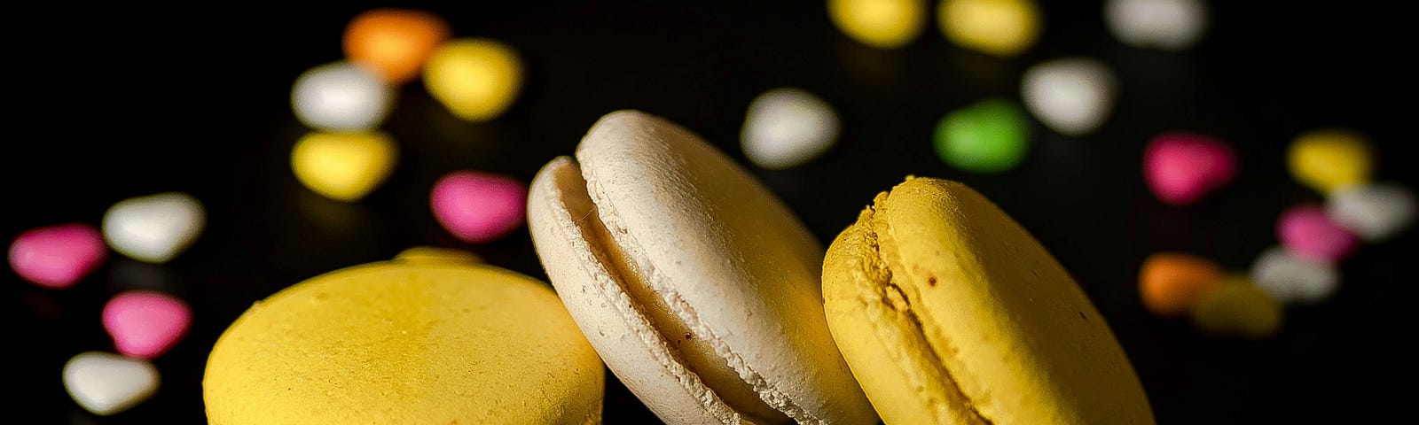 Three macaroons in the forefront with heart candies in the background