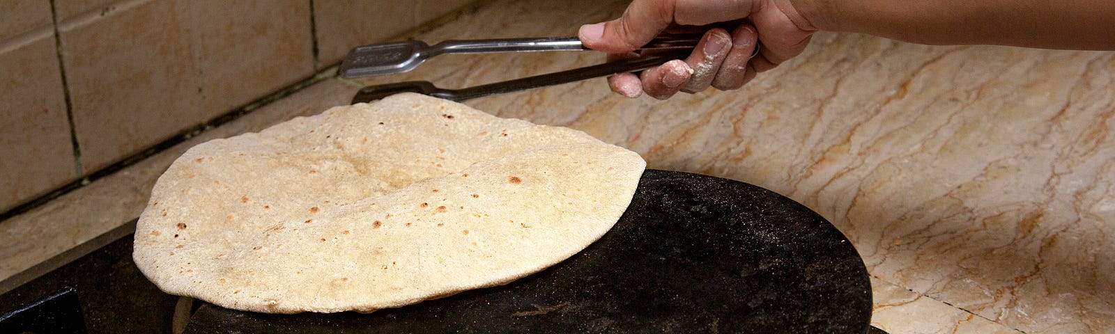someone flips a tortilla over a flat pan