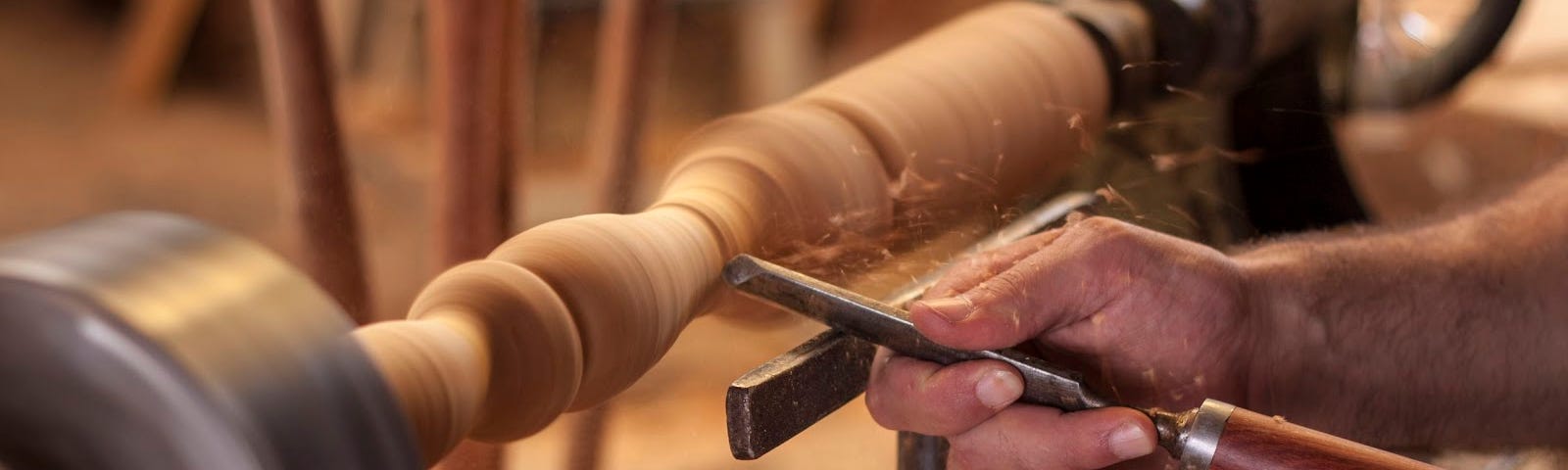A worker turning wood on a lathe