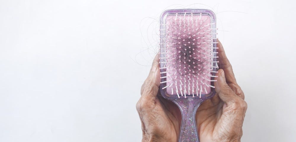 Someone holding a comb with hair tangled in it.