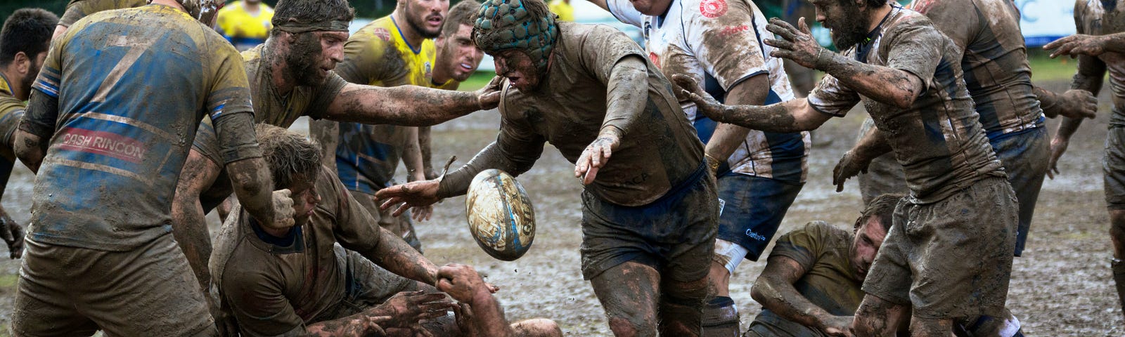 A group of rugby players competing in muddy conditions.