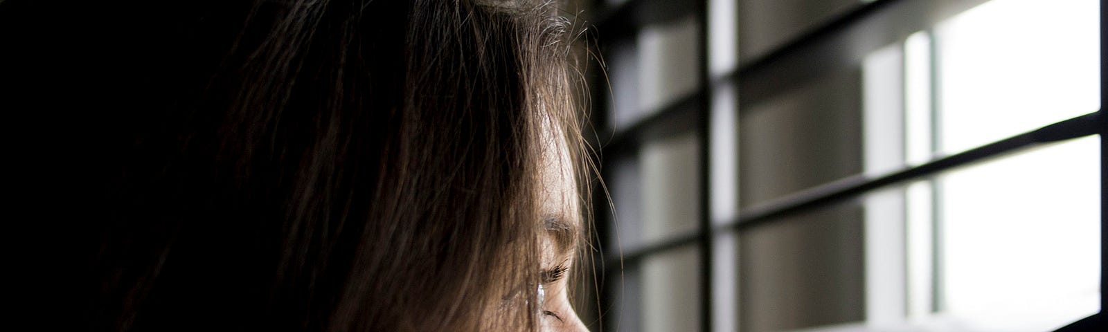 This is a photo of a young girl looking pensively out a window.