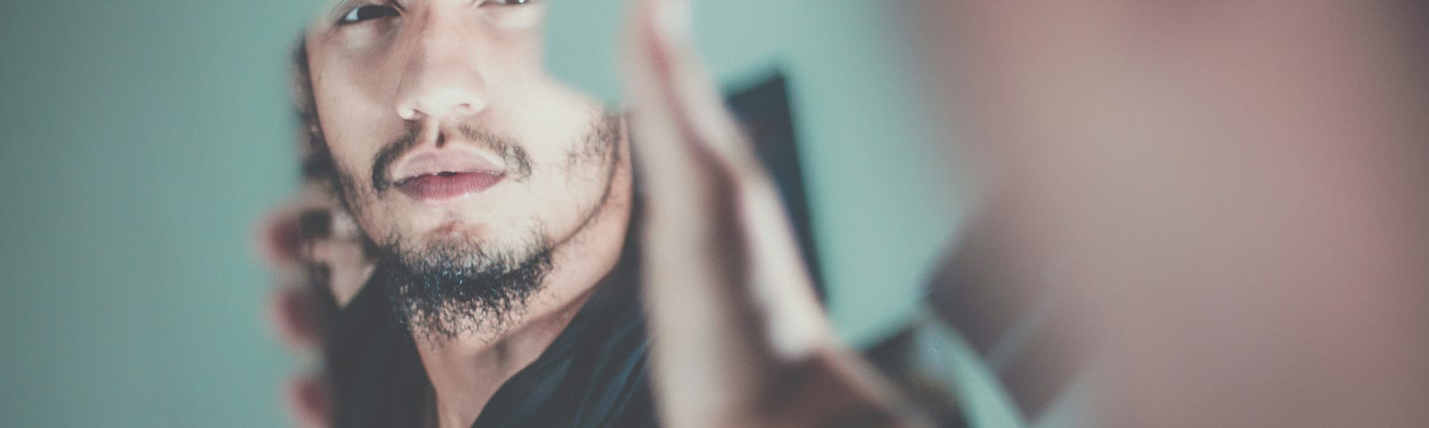 man looking at his reflection in a piece of mirror