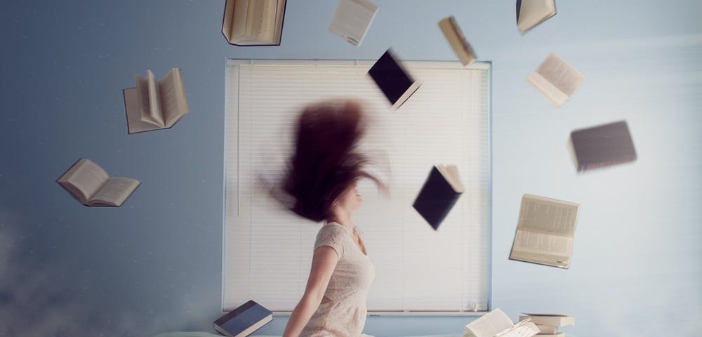 A stressed out woman who is surrounded by books flying all around.