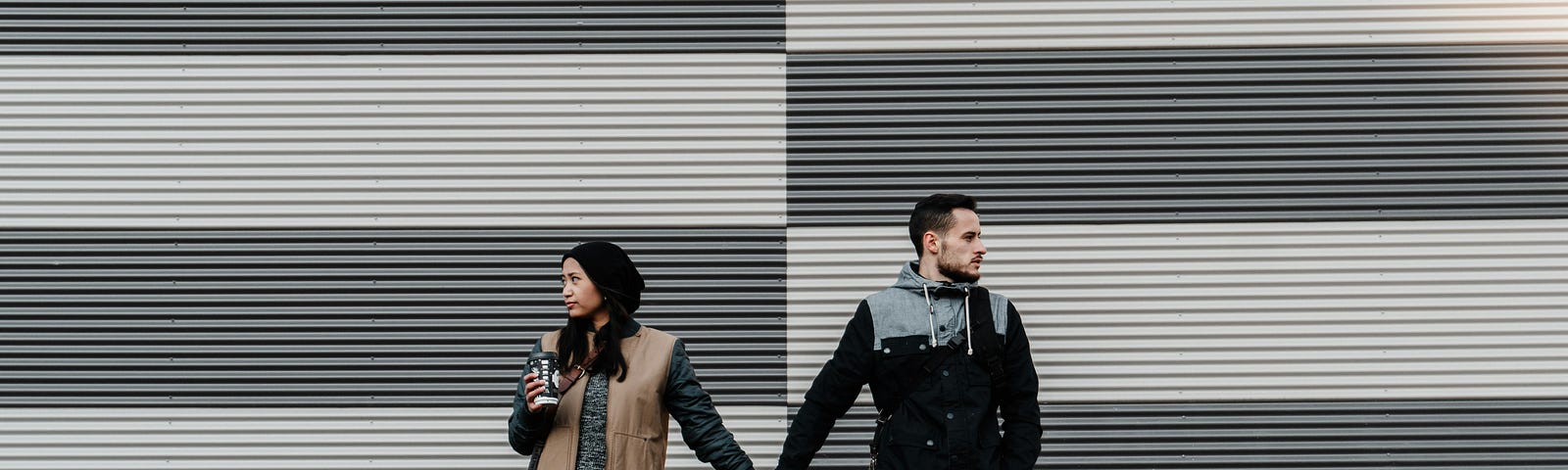 A couple holding hands but each looking in an opposite direction