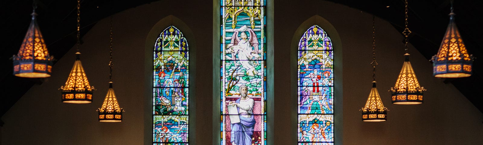 Inside view of a sanctuary with stained glass windows behind an altar