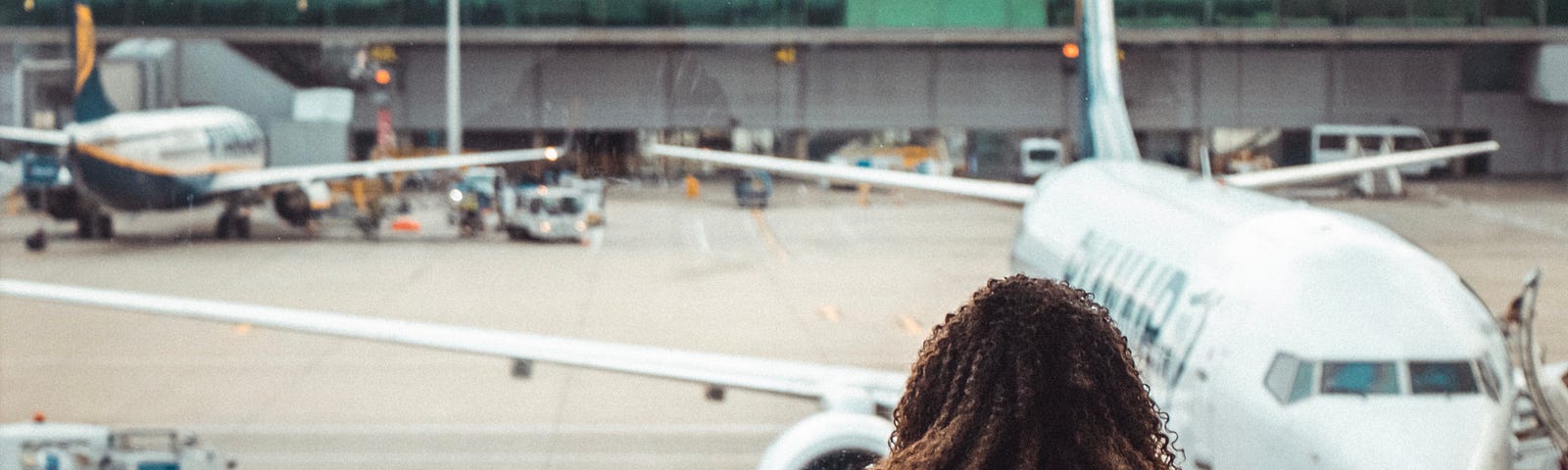 A woman stares out at a plane from a departure lounge at an airport