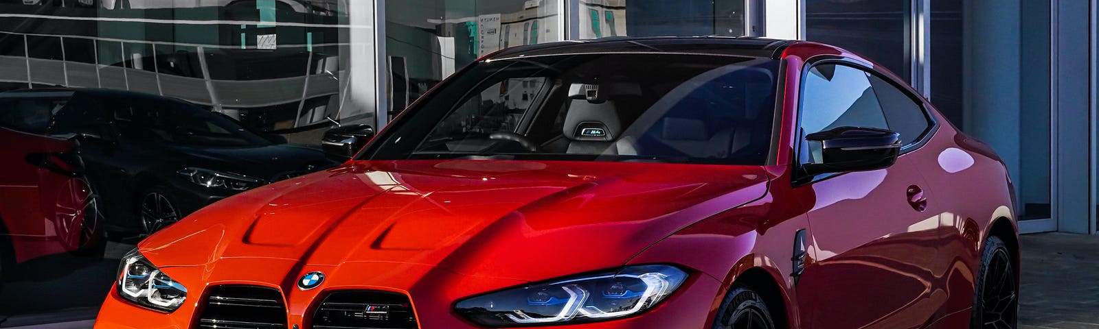 A red BMW sits parked on the city sidewalk.