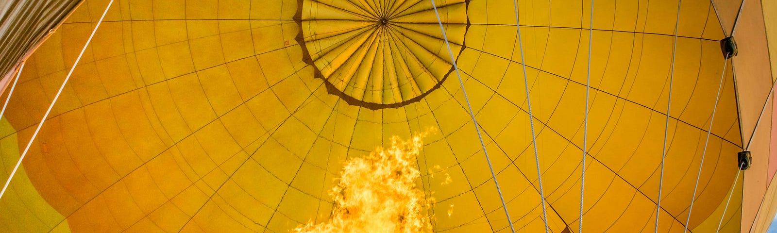Yellow and red flames firing up a bright yellow hot air balloon.
