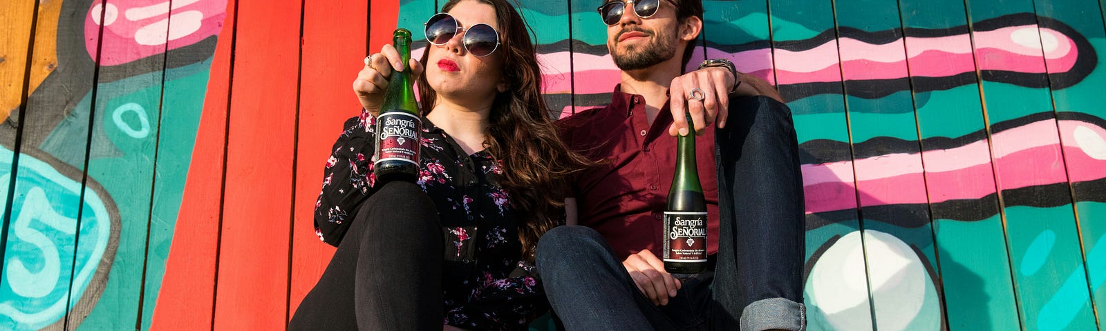 This shows a couple sitting in front of a colorful wall.