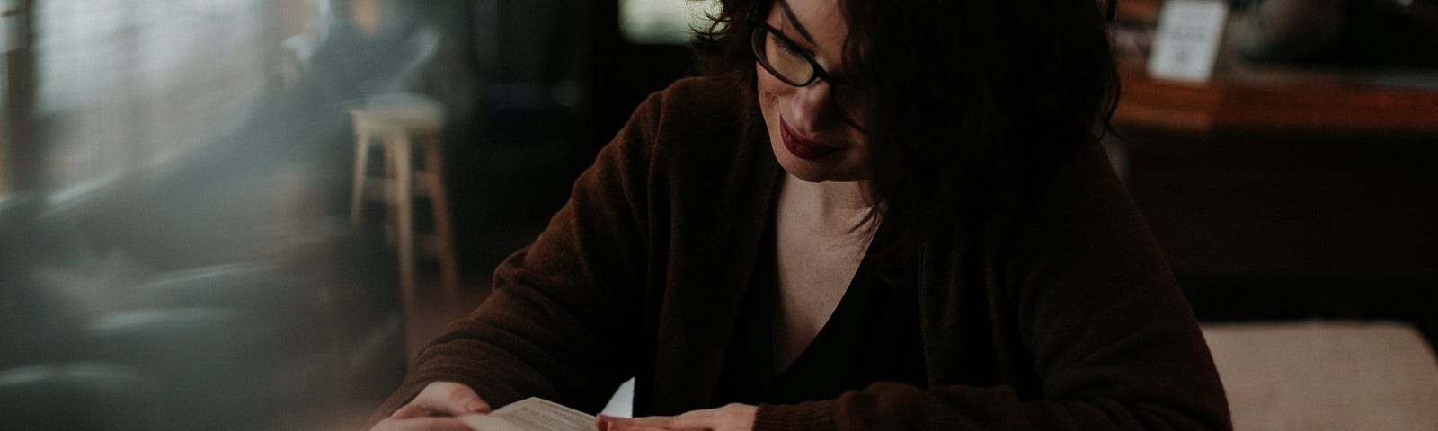A woman wearing glasses reading a book at a desk