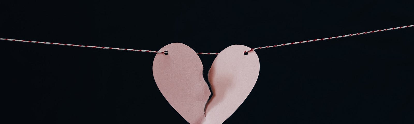 a broken pink paper heart on a string