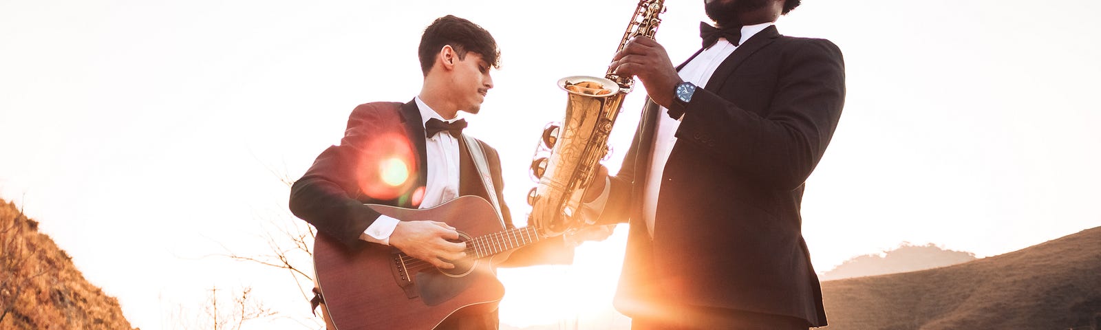 two fools in tuxedos playing an accoustic hguitar and a saxophone