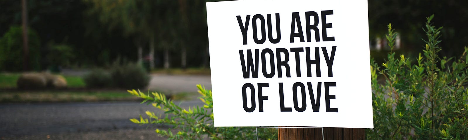 A white sign saying “you are worthy of love”