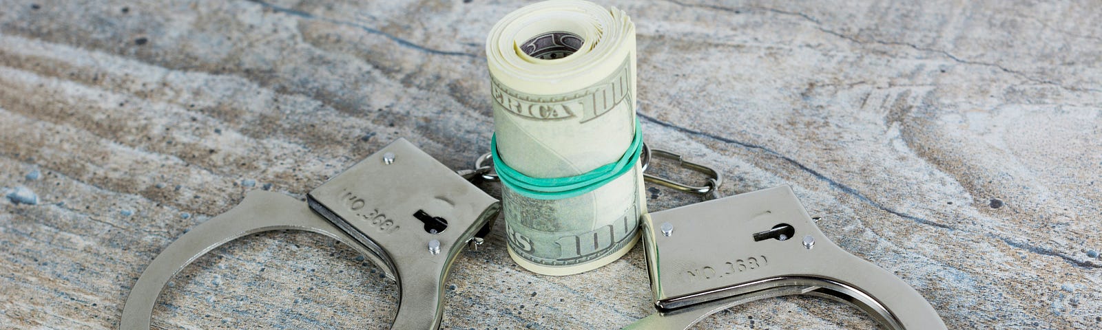 Picture of a wad of money encircled by a pair of handcuffes via Alt text on Medium