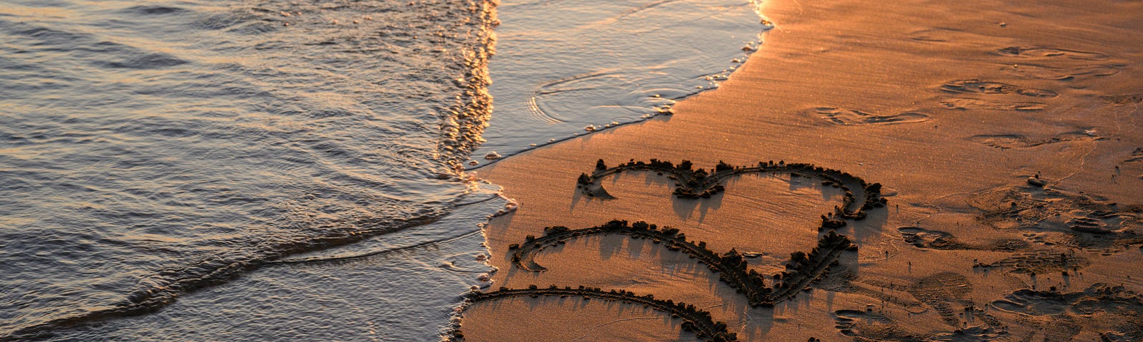 Waves washing 2023 written on beach sand