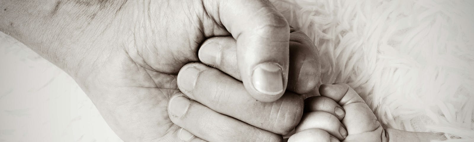 An adult and infant touch fists