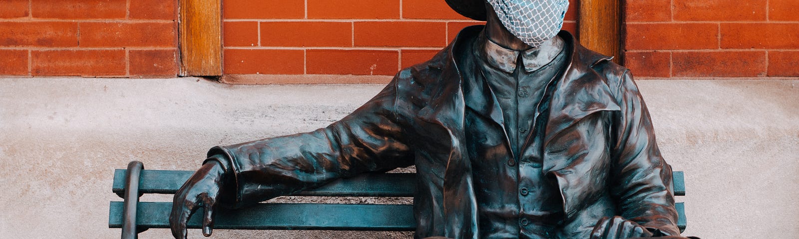 Statue of a fireman on a bench wearing a facial mask