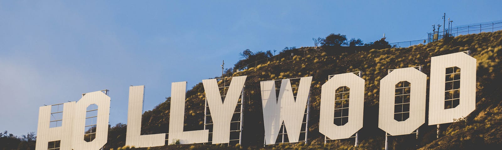 Coloured image showing the famous Hollywood sign nestled in the hills under a bright blue sky.