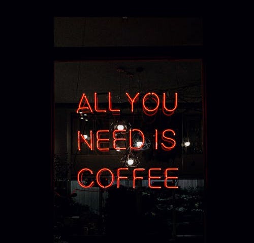 Red neon sign saying “all you need is coffee”