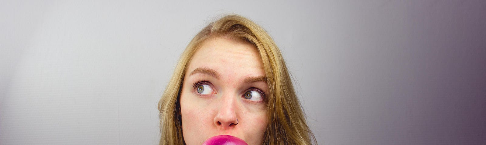 A young woman blowing bubble gum