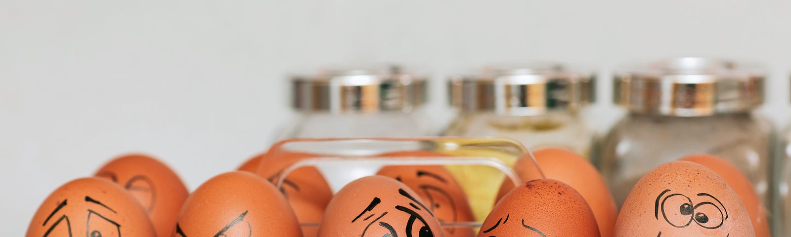 Five brown eggs with funny faces drawn on them.